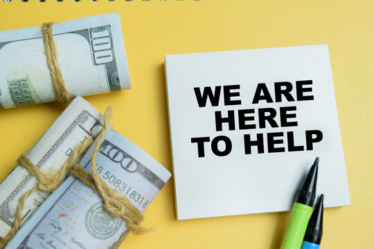 Concept of we are here to help write on sticky notes and dollar currency isolated on table.