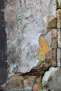 Multi layered vintage grunge wall texture with cracked plaster, peeling mint and yellow paint, showing brickwork and providing copy space.