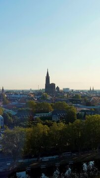 Vertical video. Strasbourg, France. The soaring Gothic spire of Notre-Dame Cathedral, its single tower rising 142 metres above the historic city centre, seen from an aerial perspective on a clear sum