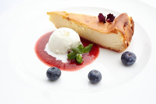 Cheesecake slice with ice cream, berry sauce and fresh blueberries