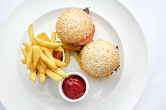 Mini burgers with french fries and ketchup on white plate