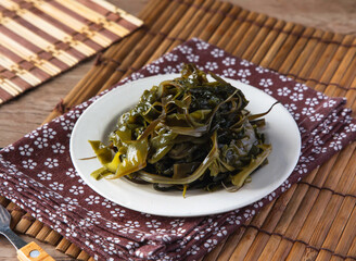 Fresh seaweed salad served on a white plate with a patterned napkin © Sana
