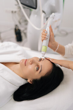 Closeup face of middle-aged woman patient receiving professional facial treatment in beauty salon, undergoing hardware mesotherapy and microneedling to rejuvenate skin and achieve anti-aging effect.