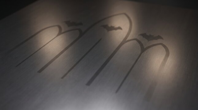 Minimalist dark grey metal surface featuring a subtle embossed of three gothic arches with small bat silhouettes above each arch