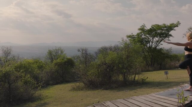 Woman finds quiet balance in tree pose above a misty hillside