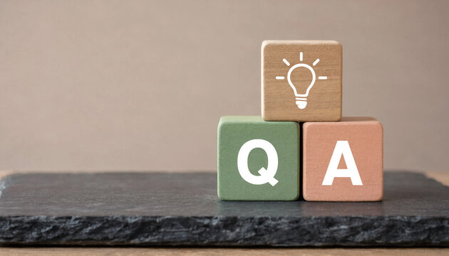 Stack of wooden cubes with letters forming the acronym QA and a lightbulb icon representing frequently asked questions