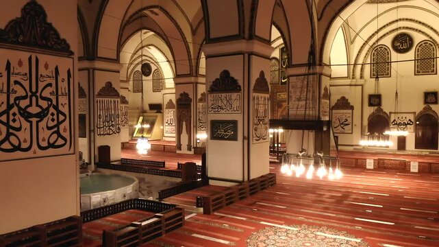 Bursa Grand Mosque interior in Turkey displays Islamic calligraphy and a spacious prayer hall.