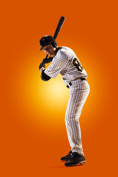 Baseball. Professional baseball player isolated on orange background. Baseball player in action