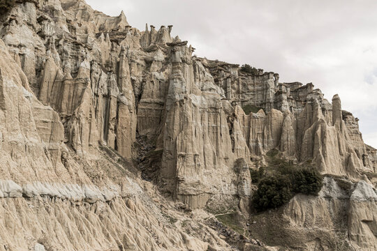 Low angle view of fairy chimneys and eroded volcanic rock formations under cloudy sky
