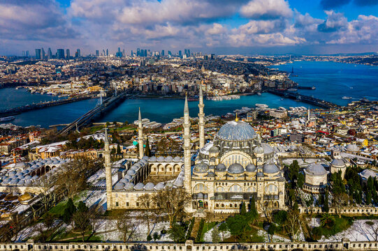 Panoramic aerial view of the historic Suleymaniye Mosque and Golden Horn covered in light winter snow, Istanbul.