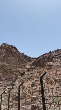 Panning shot of a arid rocky mountain landscape along a security fence in Saudi Arabia.