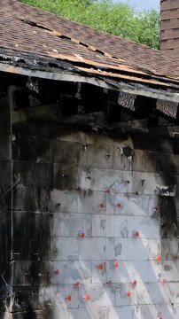 Damaged brick chimney stands on the roof of burned house. Concept of fire insurance. Arson case. Consequences of a gas or battery explosion. Home maintenance, structural repair, building inspection.