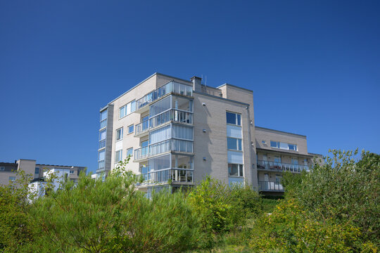 Modern apartment block rising above dense green vegetation.