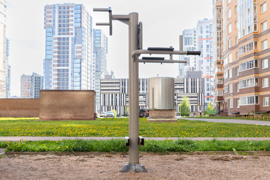 Outdoor fitness station with dip bars and abdominal exercise supports in apartment courtyard. Public calisthenics equipment. Urban exercise and bodyweight training.