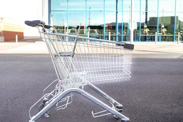 An empty shopping cart stands in front of a modern empty shopping mall © Tatiana