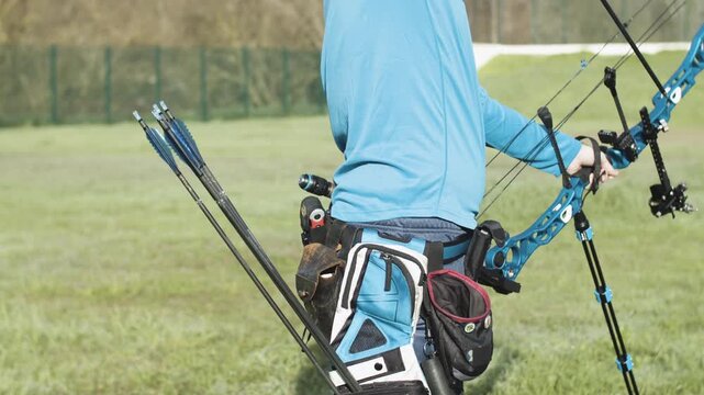 Archer Practicing Target Shooting with a Blue Compound Bow Outdoors