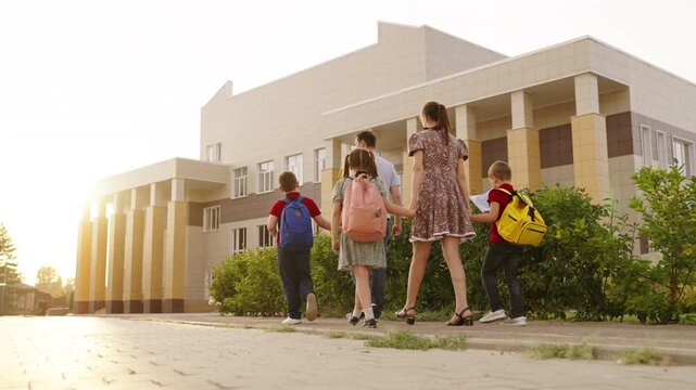 Morning routine: walk to school building, Young learners begin their academic journey, Back view of family going to school, New beginnings for eager students, Group of children attending school in the