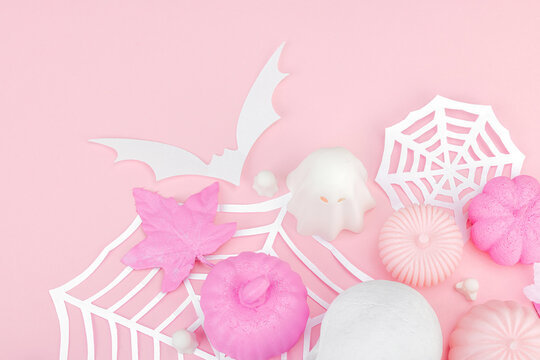 Pink Halloween flat lay with pumpkins, cute ghosts, artificial skull, bats and spider webs