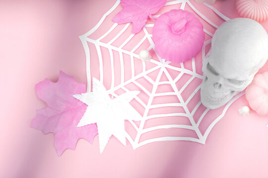 Pink Halloween flat lay with pumpkins, cute ghosts, artificial skull, bats and spider webs