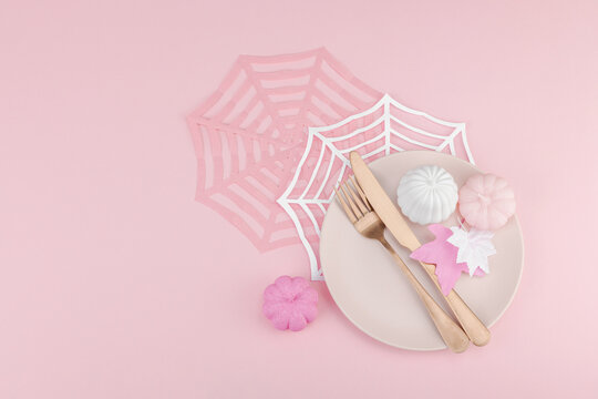 Pink Halloween table setting flat lay with plate, cutlery on rosy background