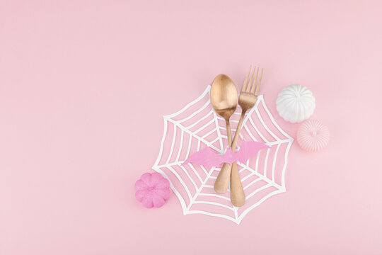 Pink Halloween table setting flat lay with plate, cutlery on rosy background