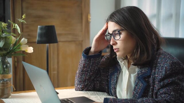Young Latina secretary feeling very frustrated in her office while working on her laptop. Concept of workplace stress, professional pressure, computer problems, frustration, productivity challenges, a
