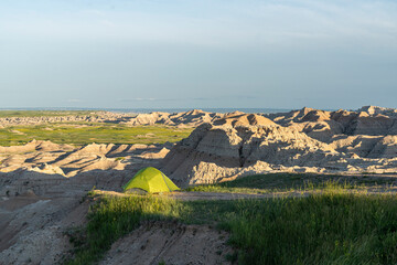Green Tent Camping on a Ridge Overlooking Badlands Rock Formations at Golden Hour © Brian