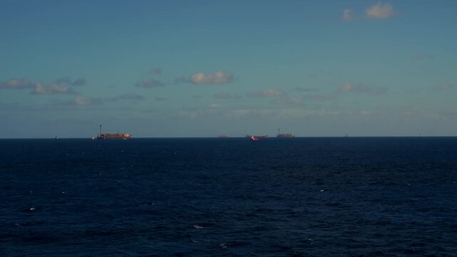Offshore oil field with multiple FPSOs, oil platforms, and vessels operating at sea. Oil and Gas Industry.