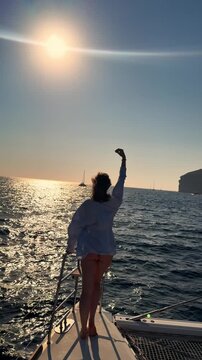 Tracking shot of woman enjoying ocean sunset on sailboat deck