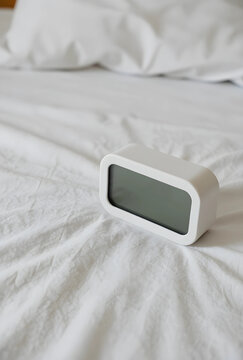 Insomnia and sleep disorder concept, digital alarm clock on messy white bed sheets morning routine and wake up time in a bedroom