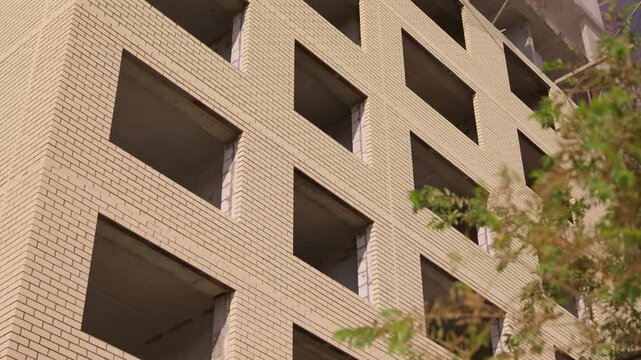 Unfinished brick facade of multistory residential building under construction