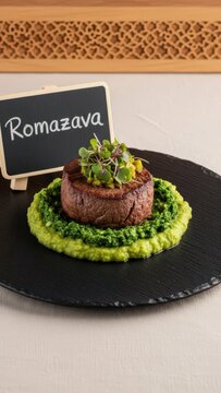 Gourmet Malagasy Romazava Beef Medallion and Anamalao Puree on Black Basalt with Chalkboard Sign and Copy Space