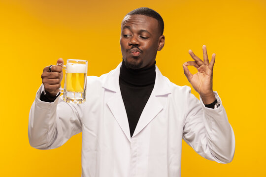 Man in lab coat appreciating a beer with an okay gesture against a warm background showcasing appreciation and satisfaction.