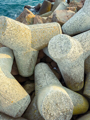 Fototapeta premium Concrete barriers on a rocky shore near the sea during daylight showing water and sky