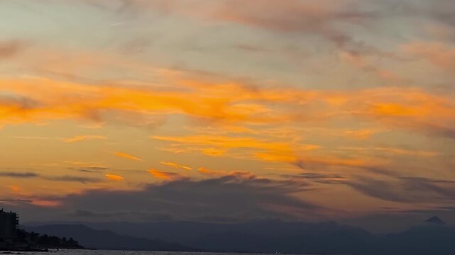 Smooth camera zoom out from colorful orange and golden sunset sky clouds to a peaceful Mediterranean sea coastline in Spain. Ideal for travel, background, meditation and relaxation videos.
