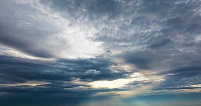 Dramatic clouds cover the sky as sunlight filters through a soft opening, casting gentle light across the atmosphere.
