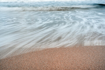Fototapeta premium long exposure of waves crashing on sandy beach