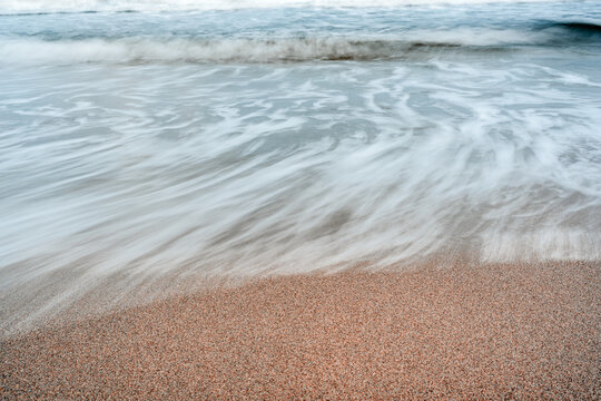 long exposure of waves crashing on sandy beach