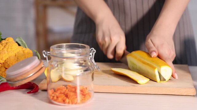 Making pickles. Woman cutting zucchini at white wooden table indoors, closeup