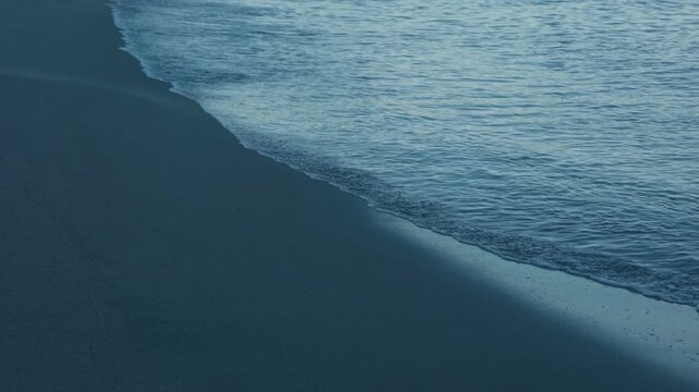 Gentle Waves Lapping Quietly on a Dark Blue Beach