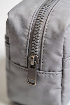 Gray fabric bag zipper detail with metal pull tab, macro
