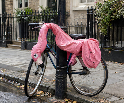 Deflated Flamingo Pool Float Draped Over Parked Bicycle