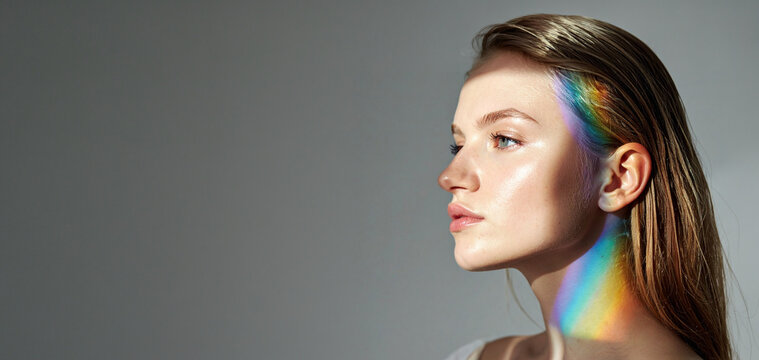 Profile portrait of a young woman with a prism rainbow light beam across her face and neck. Ideal asset for beauty skincare campaigns, mental health, wellness, and aesthetic social media content.