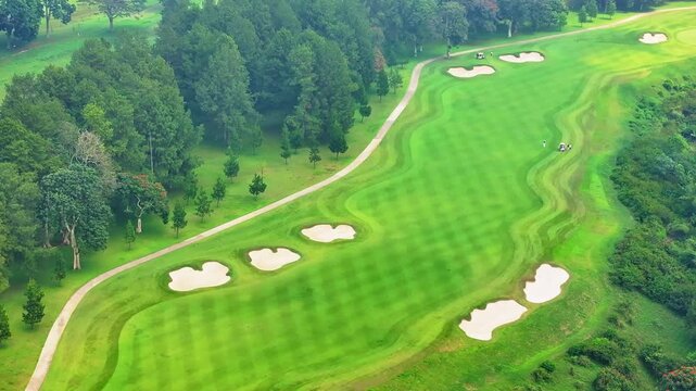 Aerial drone view of lush green golf course fairway and forest landscape