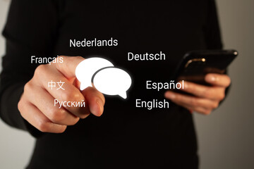 Hand points to language icons floating around smartphone © Gabriela