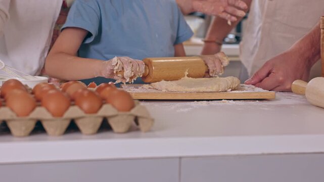 Family baking homemade bread dough together bright kitchen, rolling fresh pastry with wooden pin beside brown egg and flour, joyful cooking activity featuring children and adults creating rustic food