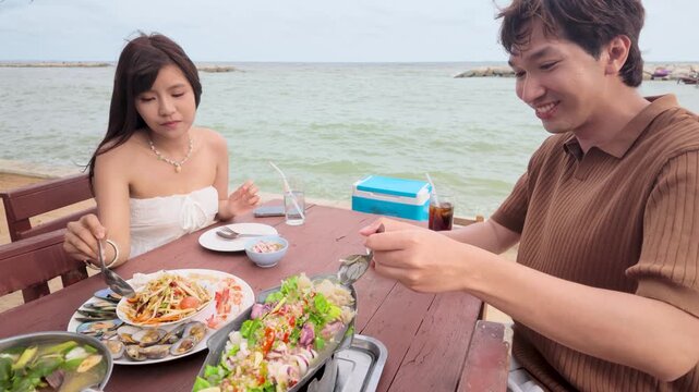 Asian Couple Having Seafood Lunch at Outdoor Beachside Restaurant