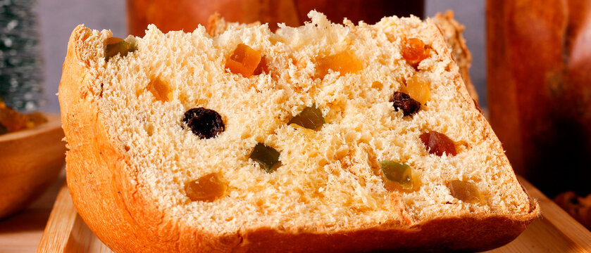 Traditional Christmas panettone presented as a generous slice, highlighting the soft dough, candied fruit, in a festive setting.