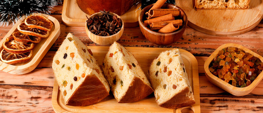 Slices of classic panettone showing delicate dough, candied fruit and raisins in a festive Christmas arrangement.