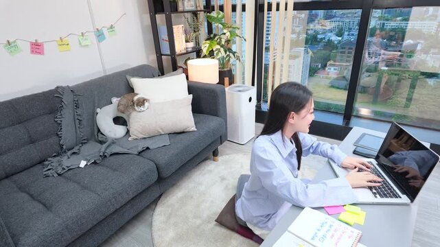 Asian Freelancer Working on Laptop in Modern Living Room Apartment